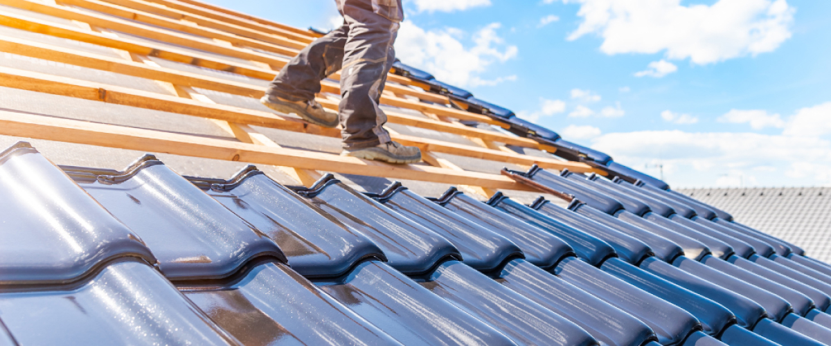 A man standing on top of a unfinished roof.